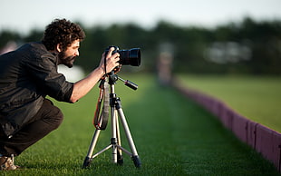 man wearing black cuff-sleeved shirt and black pants taking a picture with his black DSLR camera with tripod HD wallpaper